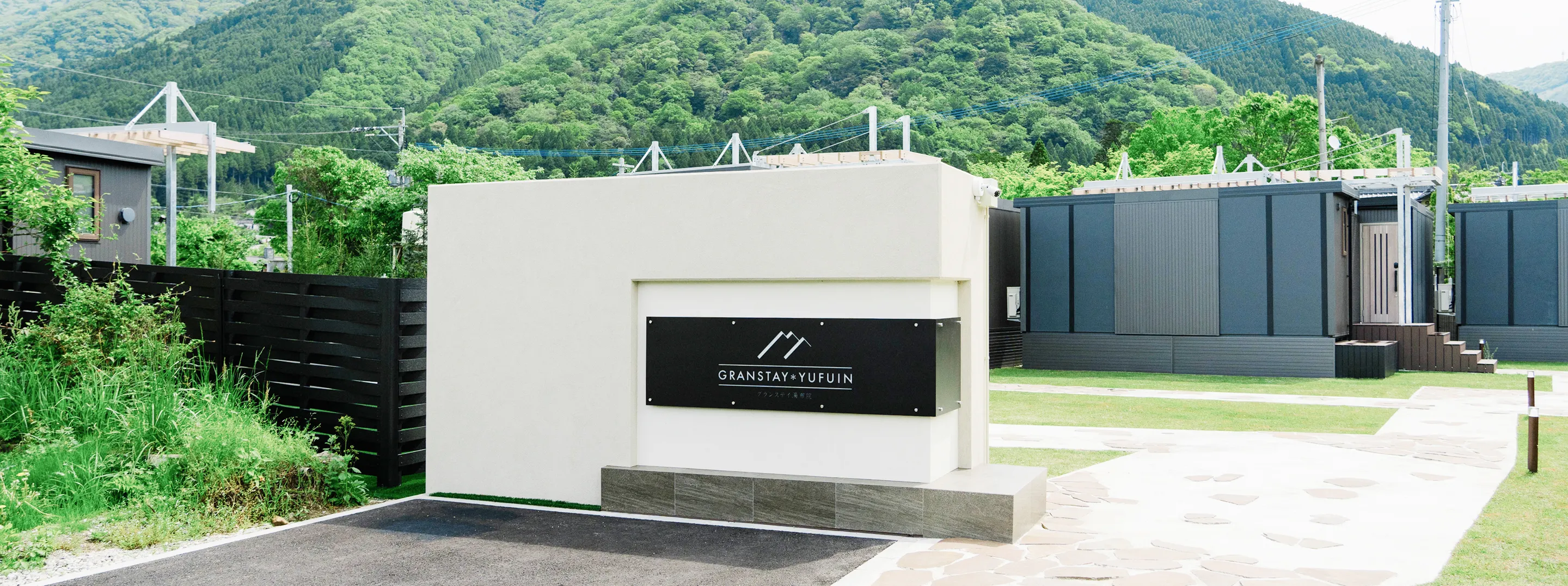 「GRANSTAY YUFUIN」のロゴ看板が設置された、山々を背景とする宿泊施設のエントランス風景