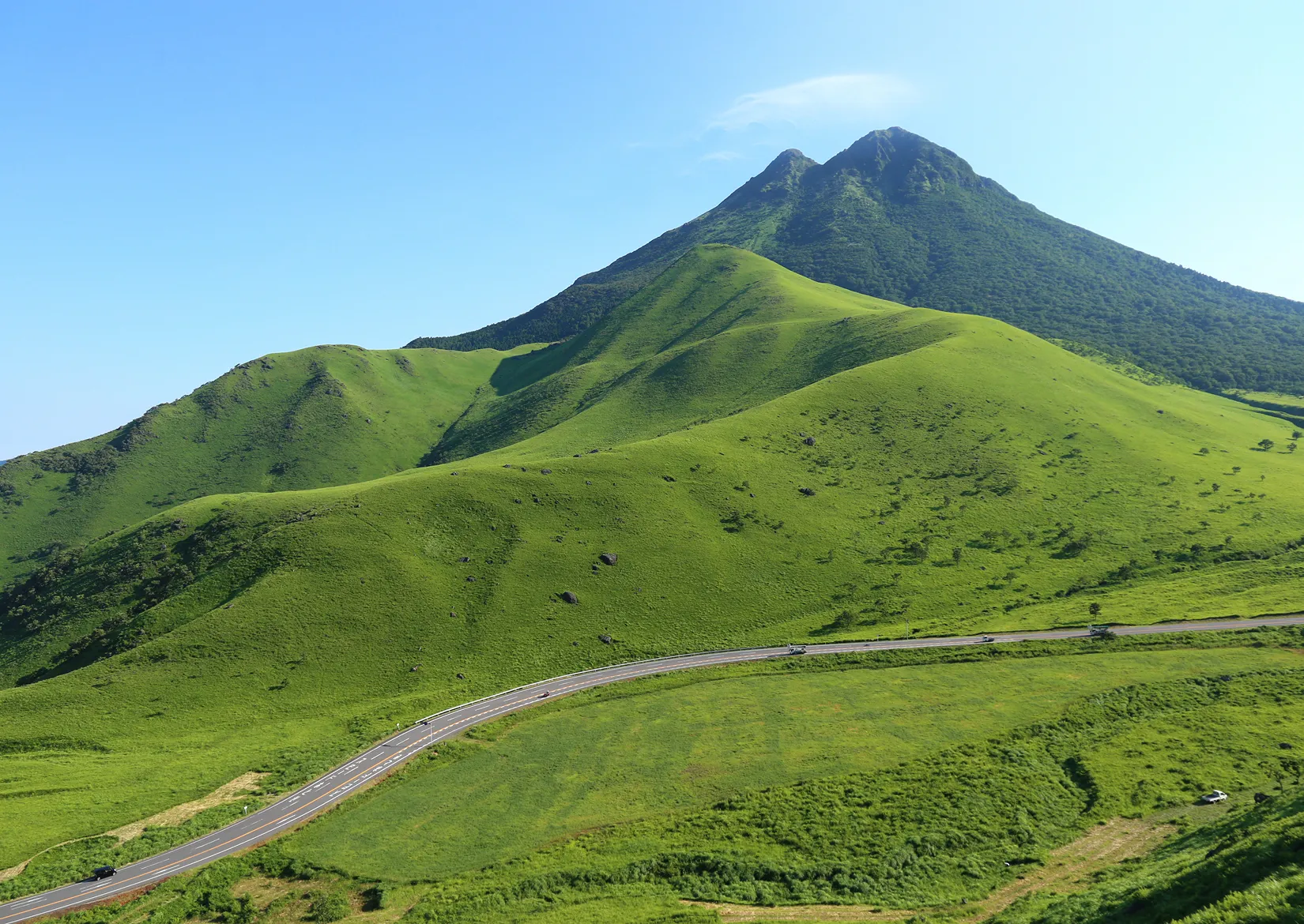 青空の下に広がる由布岳の草原と道路